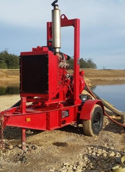 bright red water pump near water at a construction site.